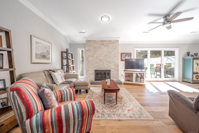 living area with ceiling fan, a fireplace, ornamental molding, and wood finished floors