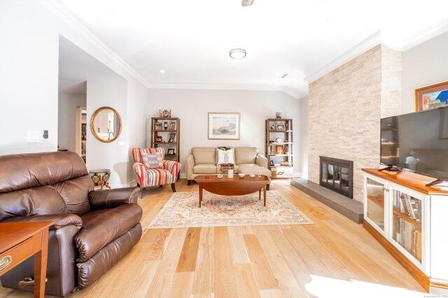 living area featuring vaulted ceiling, a stone fireplace, ornamental molding, and wood finished floors