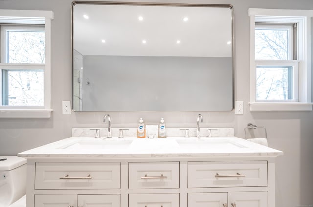 full bathroom with double vanity, a sink, toilet, and recessed lighting