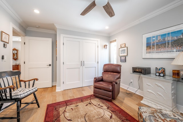 living area featuring light wood-style floors, crown molding, baseboards, and a ceiling fan