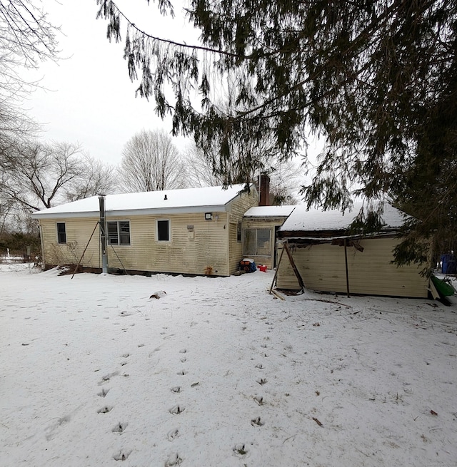 snow covered back of property featuring brick siding