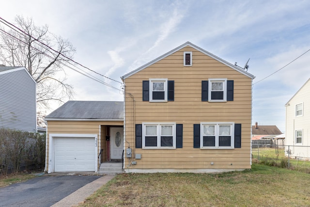 traditional-style house with aphalt driveway, an attached garage, fence, and a front yard