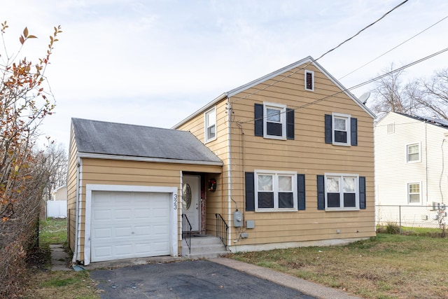 traditional-style home featuring driveway, roof with shingles, an attached garage, and fence