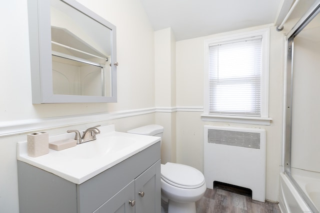 full bath featuring toilet, wood finished floors, vanity, vaulted ceiling, and radiator