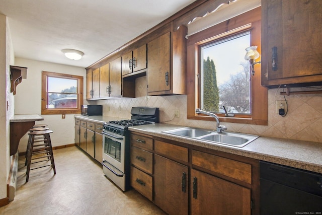 kitchen featuring decorative backsplash, baseboards, a sink, and black appliances