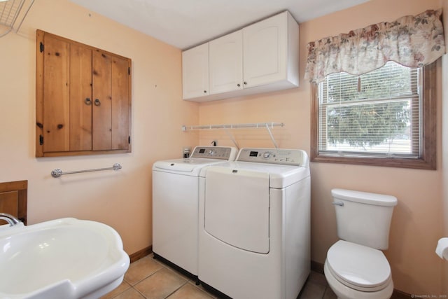 washroom featuring washing machine and clothes dryer, light tile patterned flooring, a sink, laundry area, and baseboards