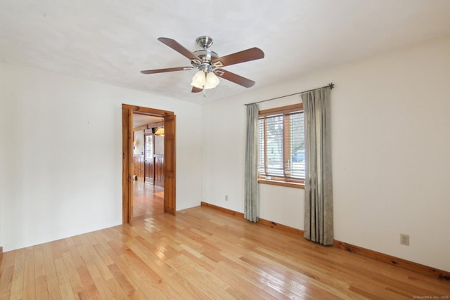 spare room with a ceiling fan, light wood-style flooring, and baseboards