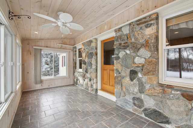 unfurnished living room featuring wooden ceiling, ceiling fan, vaulted ceiling, and wood walls