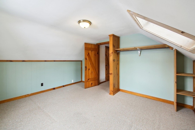 additional living space with lofted ceiling with skylight, baseboards, and light colored carpet