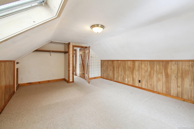 additional living space featuring lofted ceiling, light colored carpet, wood walls, and baseboards