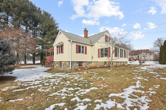 view of snow covered exterior with stairs, a chimney, and stucco siding