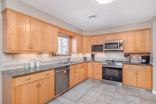 kitchen with stainless steel appliances, visible vents, a sink, and decorative backsplash