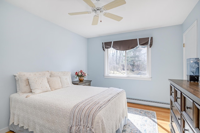 bedroom with light wood finished floors, baseboard heating, and a ceiling fan