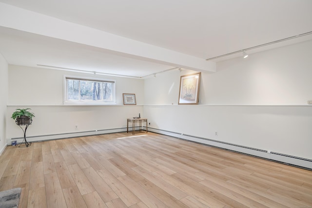 empty room with light wood-type flooring, beam ceiling, a baseboard heating unit, and track lighting