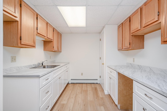 kitchen featuring light wood-style floors, a baseboard radiator, light countertops, and a sink