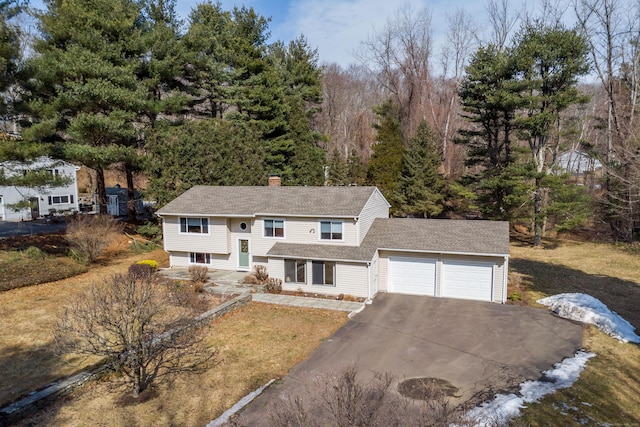 split foyer home with a garage, driveway, and a chimney