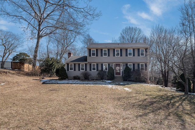 colonial house with a chimney and a front yard