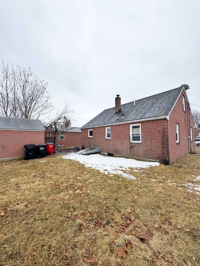 back of property featuring a yard, brick siding, and a chimney