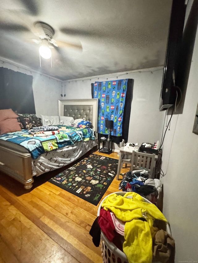 bedroom featuring a textured ceiling, ceiling fan, and wood finished floors