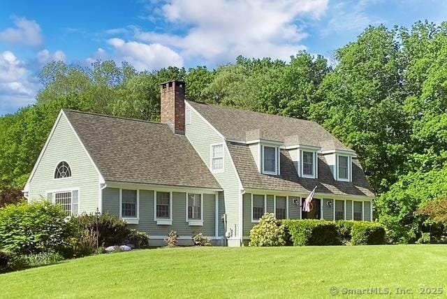 view of front of property featuring a shingled roof, a chimney, a gambrel roof, and a front yard