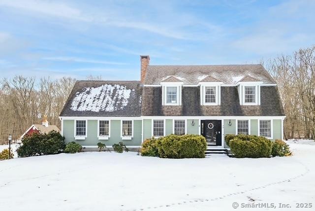 view of front of home with a shingled roof and a chimney