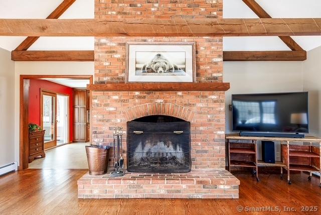 living room featuring vaulted ceiling with beams, a fireplace, and wood finished floors