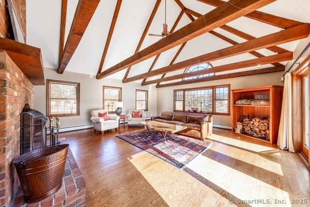 living room with a baseboard radiator, wood finished floors, and a healthy amount of sunlight