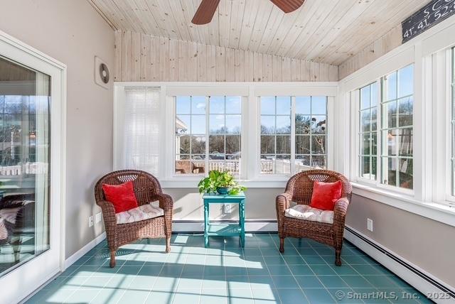 sunroom with lofted ceiling, baseboard heating, plenty of natural light, and wooden ceiling