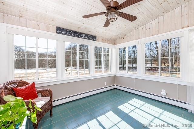 unfurnished sunroom featuring a ceiling fan, a baseboard radiator, wood ceiling, and vaulted ceiling