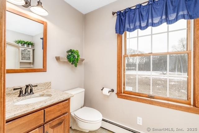 bathroom with a baseboard heating unit, toilet, and vanity