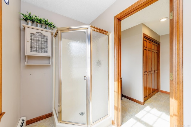 full bath featuring a baseboard radiator, a shower stall, baseboards, and a textured ceiling