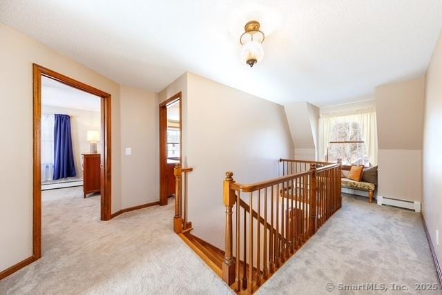 hallway with a baseboard radiator, baseboard heating, light carpet, an upstairs landing, and baseboards