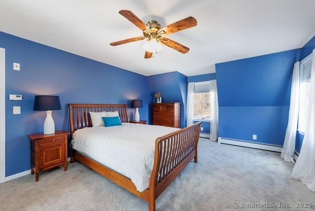 carpeted bedroom featuring lofted ceiling, a baseboard radiator, a ceiling fan, and baseboards