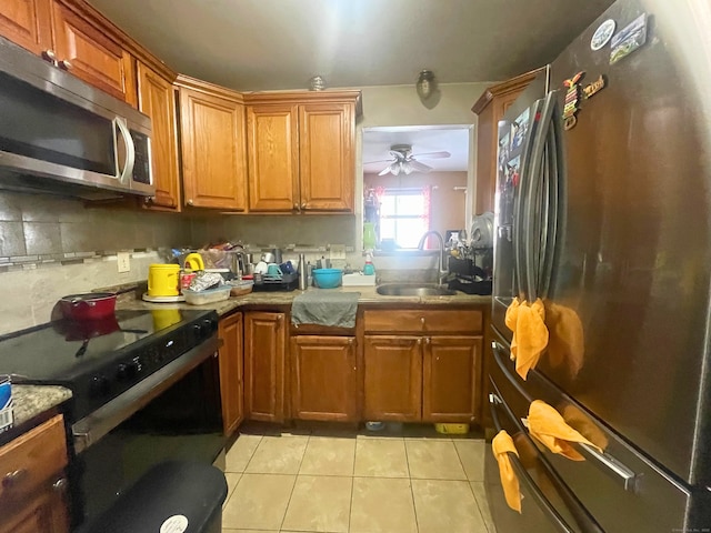 kitchen featuring appliances with stainless steel finishes, brown cabinetry, a sink, and light countertops