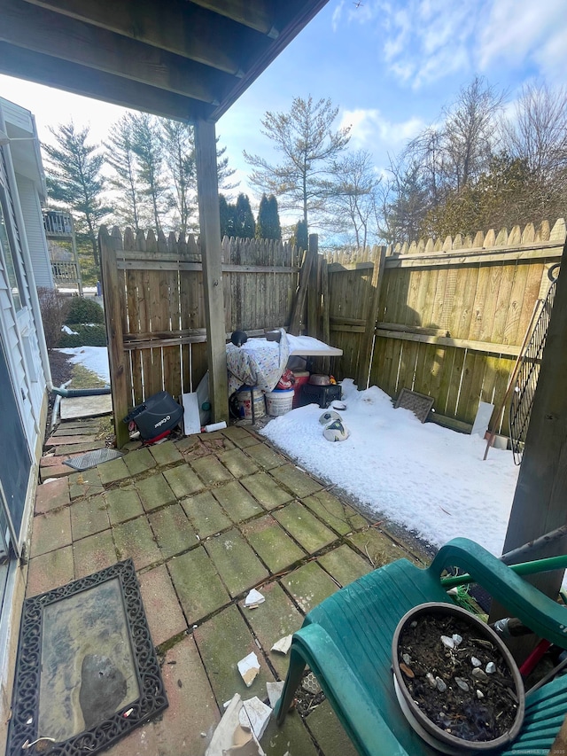 snowy yard featuring a patio area and fence