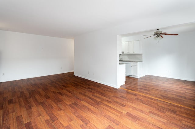 unfurnished living room featuring a ceiling fan, dark wood finished floors, and baseboards