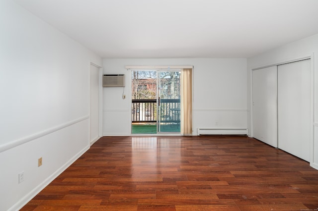 unfurnished bedroom featuring access to exterior, a baseboard heating unit, dark wood finished floors, and a wall mounted AC