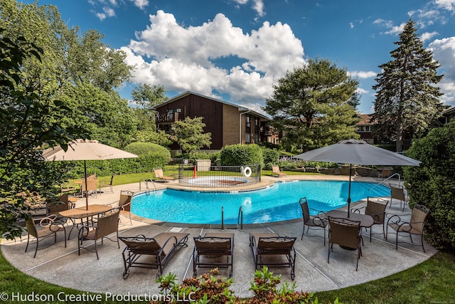 pool with a patio area, fence, and a jacuzzi