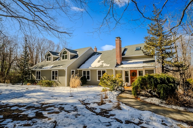 snow covered back of property with a chimney