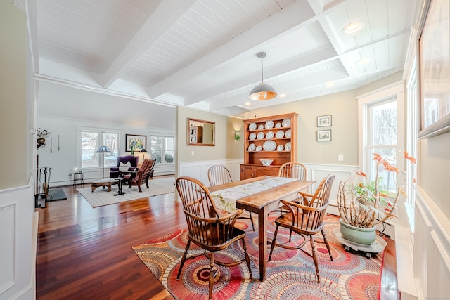 dining space with a wainscoted wall, beamed ceiling, a baseboard radiator, and wood finished floors