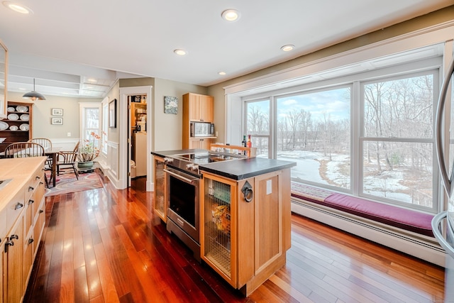 kitchen with stainless steel appliances, dark wood finished floors, baseboard heating, and a kitchen island