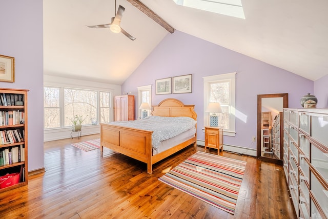 bedroom featuring a skylight, a baseboard heating unit, hardwood / wood-style flooring, and beamed ceiling