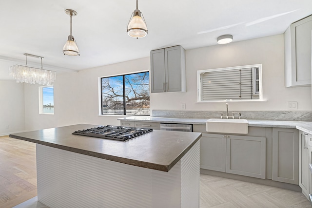 kitchen featuring a kitchen island, hanging light fixtures, stainless steel appliances, gray cabinetry, and a sink