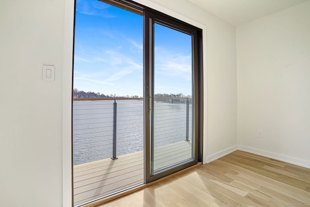 spare room featuring a water view, baseboards, and wood finished floors