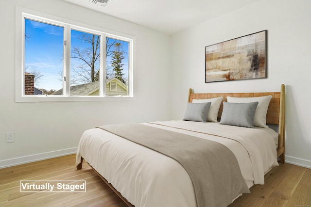 bedroom featuring wood finished floors, visible vents, and baseboards