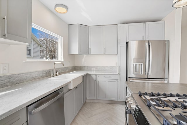 kitchen featuring appliances with stainless steel finishes, a sink, and light stone counters