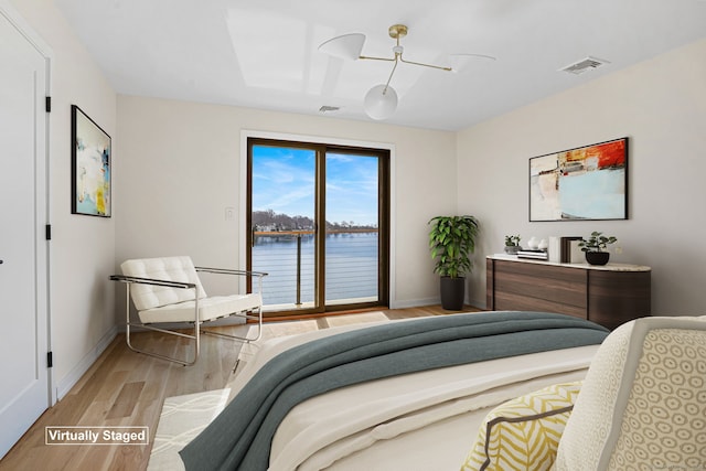 bedroom featuring access to exterior, visible vents, light wood-style floors, and a water view