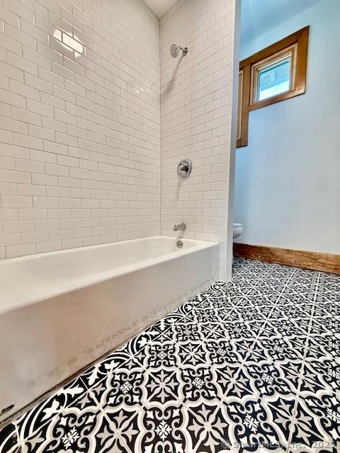 bathroom with tile patterned flooring, washtub / shower combination, and baseboards