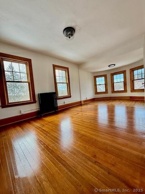 unfurnished living room featuring plenty of natural light, baseboards, and hardwood / wood-style flooring