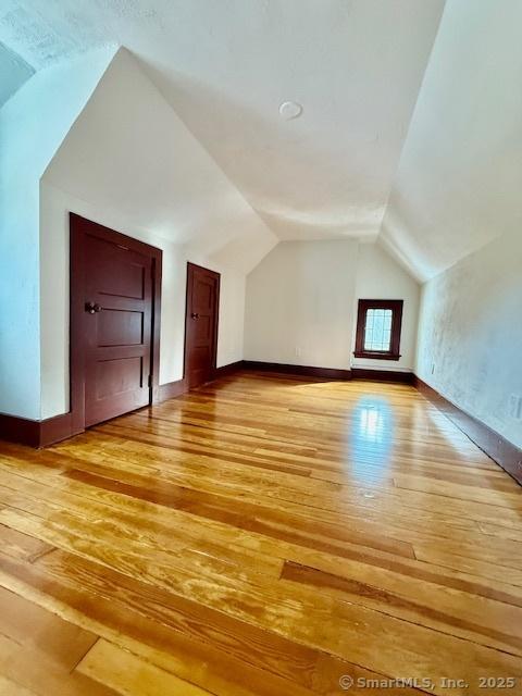 bonus room featuring lofted ceiling, baseboards, and light wood-style floors